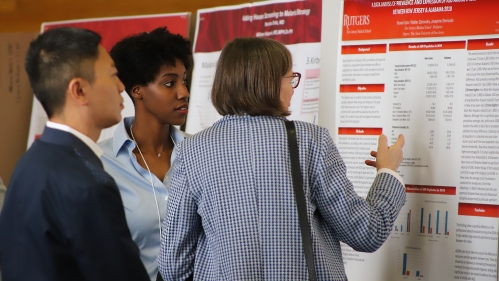 People viewing informational poster board at an event.