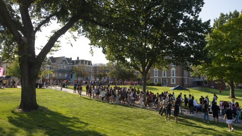 Students walking on sidewalk near grass.
