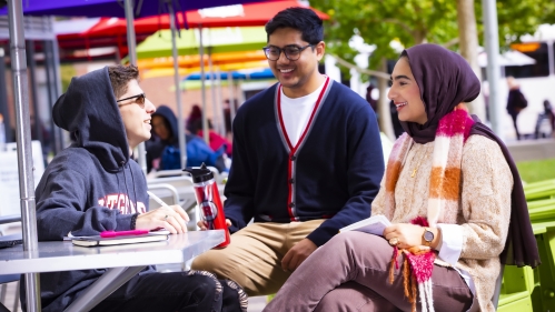 Three students sitting outside and talking.
