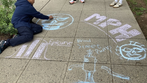Person drawing with chalk on sidewalk. 