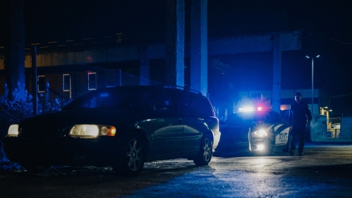 Car pulled over by cop car at night.