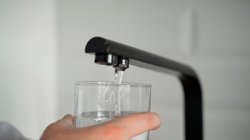 Person pouring water from tap.