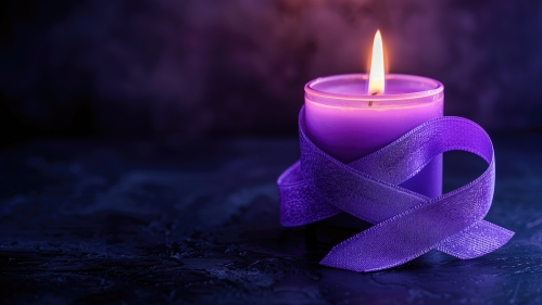 A lit purple candle wrapped with a matching ribbon