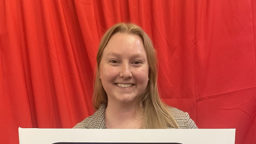 student smiling at camera with 'public health saves' lives sign