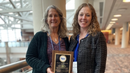 Two people holding award.