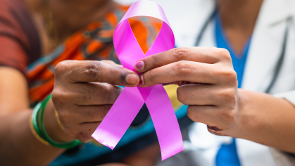 Two people holding purple ribbon.