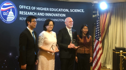 Three people holding award.