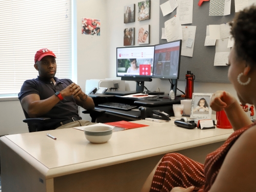 Person in hat talking to student. 