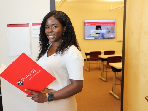 Student holding red folder and looking at camera.