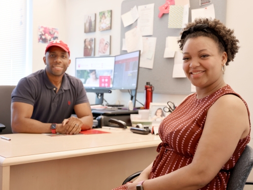 Two people sitting down and looking at camera.