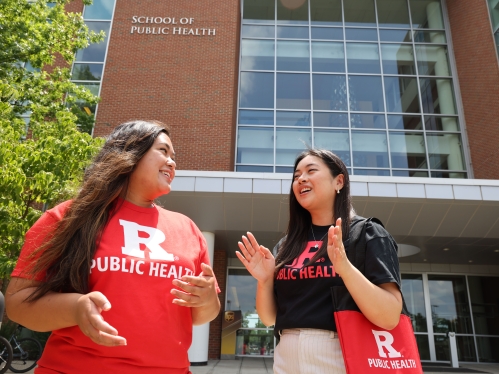 Two students in front of Rutgers SPH building speaking.