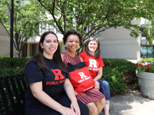 Three people sitting on bench smiling at camera.