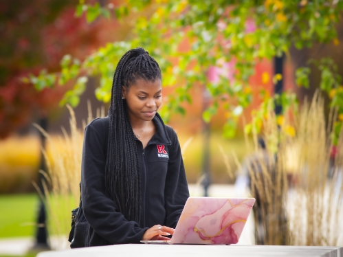 Student working on laptop outside.