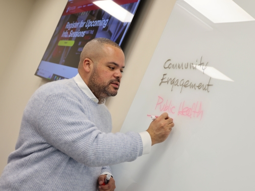 Professor writing on a whiteboard.