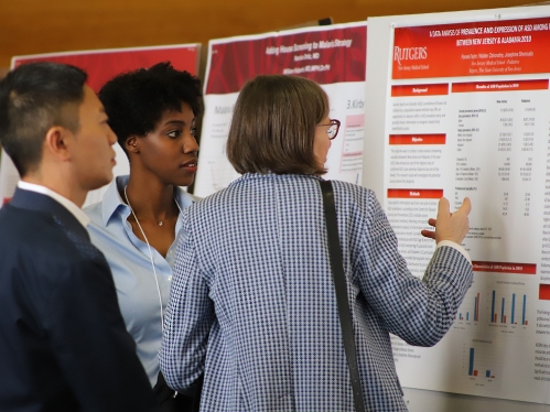 People viewing informational poster board at an event.