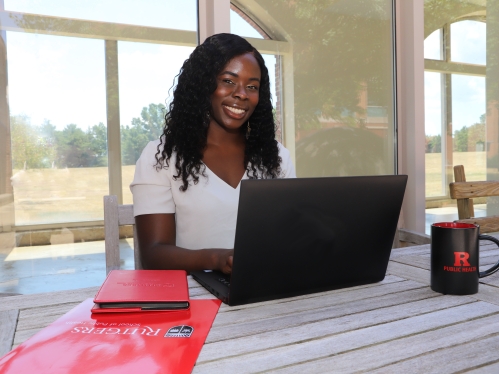 A student working on a laptop and smiling for the camera.