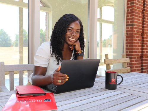 A student working on a laptop and smiling for the camera.