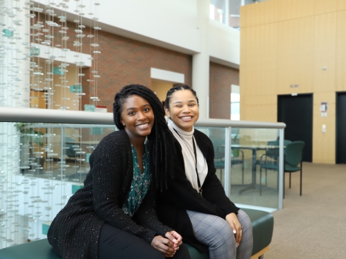 Two people sitting and smiling for the camera.