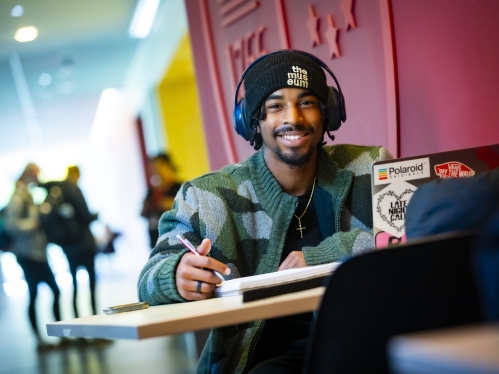 Student with headphones smiling at camera