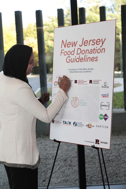 Sara Elnakib autographs the newly-released New Jersey Food Donation Guidelines.