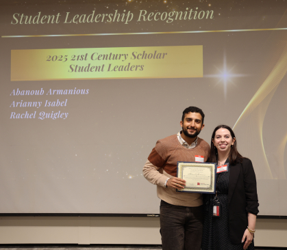 Two people posing for a photo with an award. 