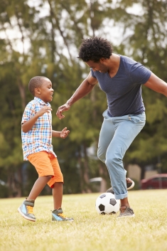 Adult playing soccer with child