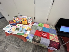 table with artwork and quilt made by faculty and staff